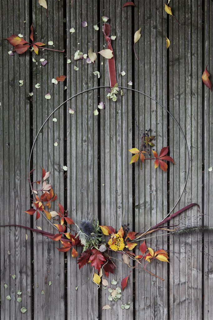 Kranz binden im Herbst mit Herbstblumen in rot-gelben Farben auf Holzboden