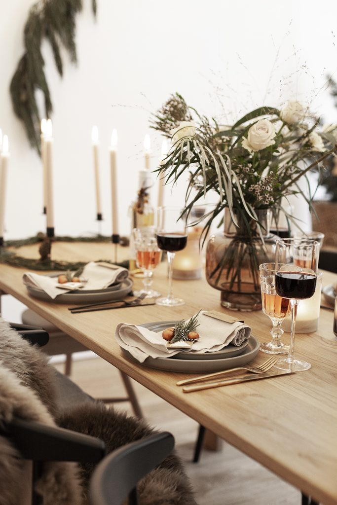 Skandinavische Tischdekoration mit Tellern und Blumenvase zu Weihnachten