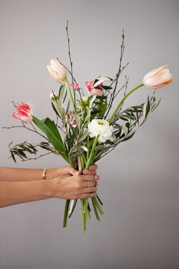 Frühlings Blumenstrauß in Hand haltend mit Französischer Tulpe, Papageientulpe, Hyazinthen, Ranunkeln, Birkenzweige, Olivenzweige