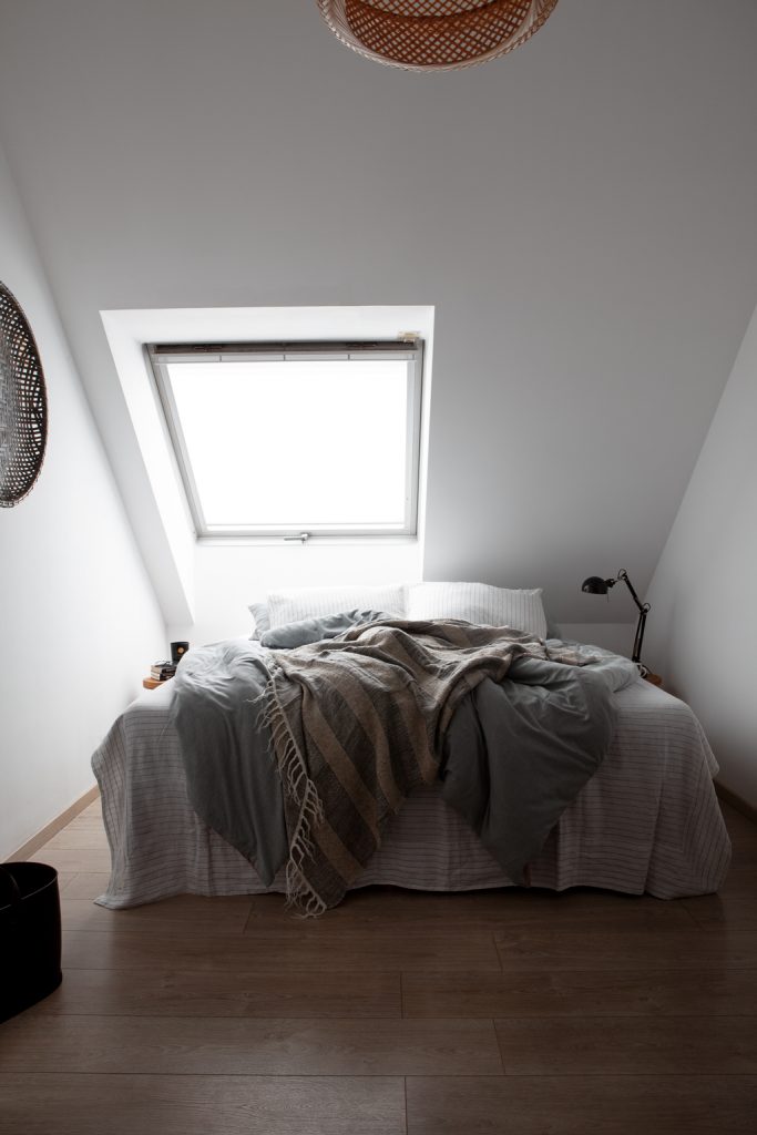 Schlafzimmer mit Bett unter Dachschräge , Bettwäsche in Grau-und Schwarz/Weißtönen gehalten von byNord -von Hej.Hem Interior