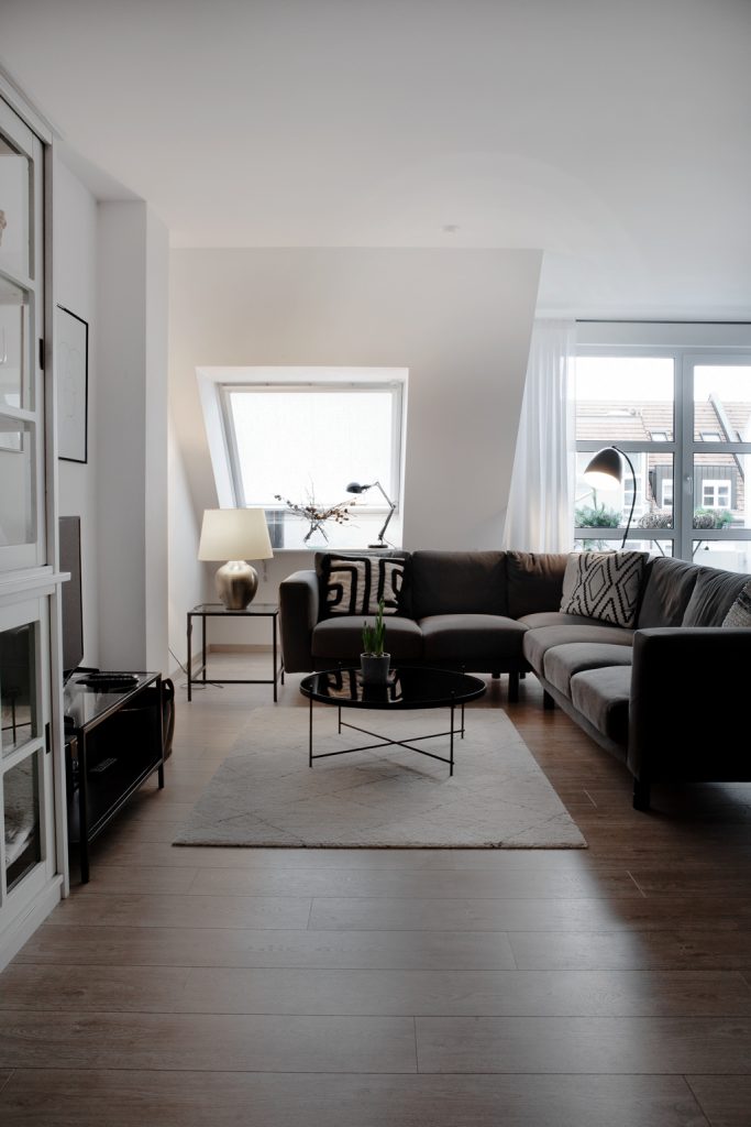 monochromes Wohnzimmer mit grauem Sofa, Wohnzimmertisch in Schwarz und hellen Teppich - von Hej.Hem Interior